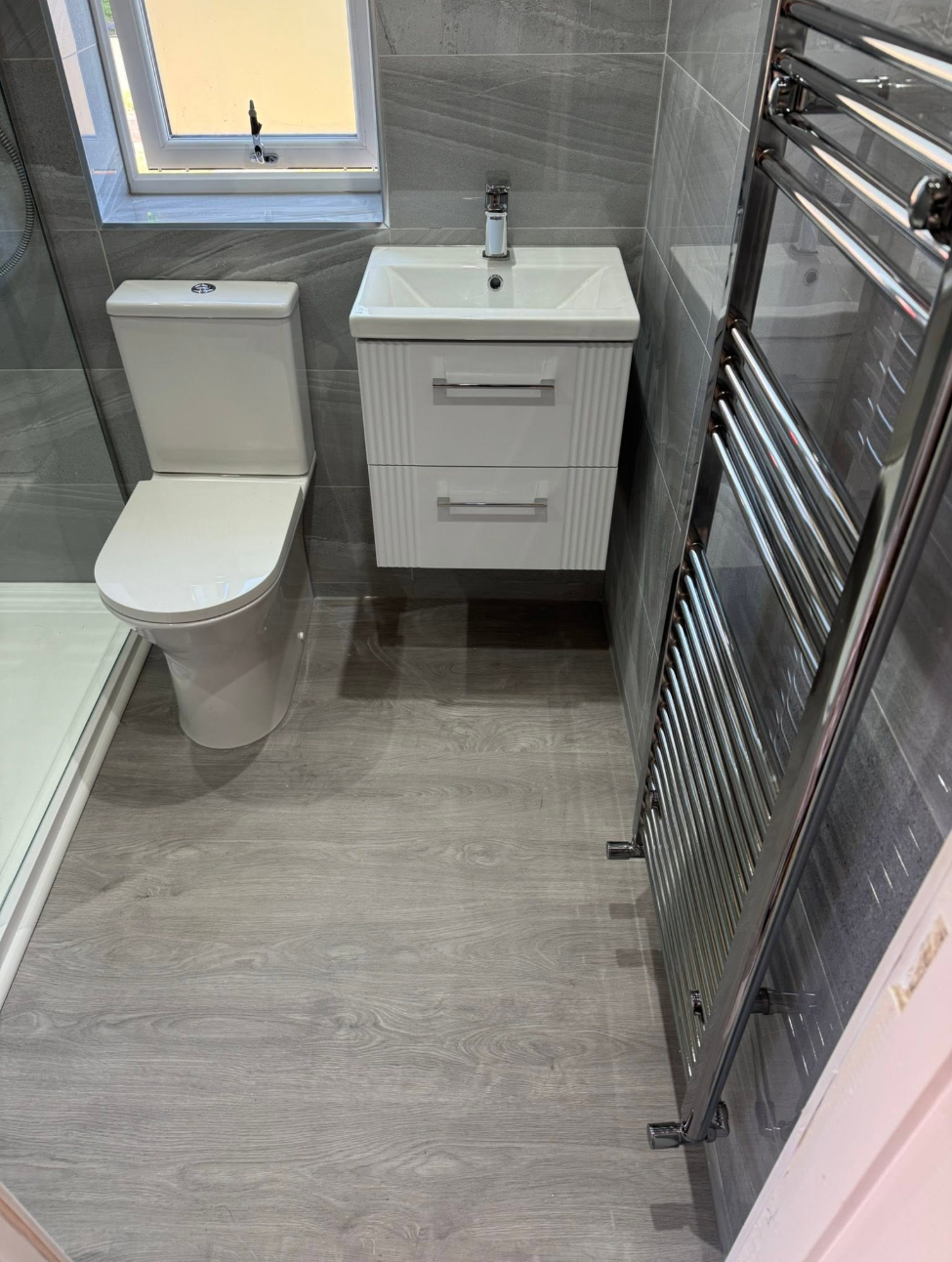 Compact bathroom with wall-hung vanity and chrome towel radiator