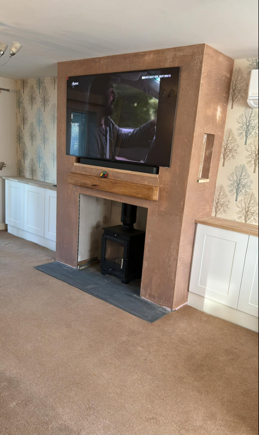 Chimney breast with wood burner, oak beam and wall-mounted TV above